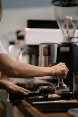 Young barista making coffee, coffee preparation service concept.