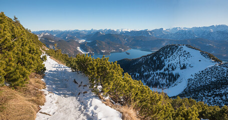 alpine trail Herzogstand with snowy footpath, view to the alps and lake Walchensee, upper bavarian landscape