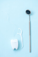 Dental mirror with a plastic toothpick with dental floss and dental floss on a blue background...