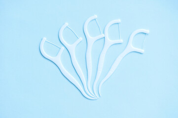 Plastic toothpick with dental floss on blue background