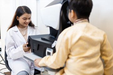 Indian female doctor optometrist using ophthalmology equipment scan checkup iris examines for patient kid male in clinic.