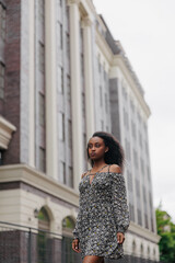 Fototapeta premium Young african pensive woman walks in city near building.