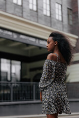 Young african pensive woman standing in city against background of building.