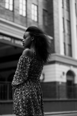 Young african pensive woman standing in city against background of building.