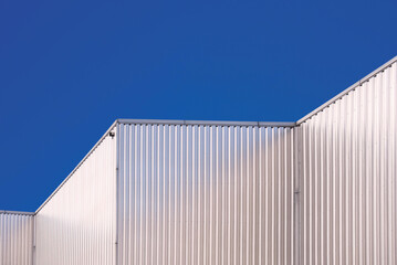 Fototapeta na wymiar Aluminum Corrugated Industrial Building against blue clear sky Background in low angle and Perspective side view