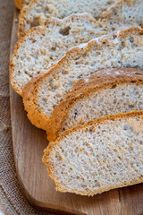 Sliced bread, traditional sourdough homemade bread loaf cut into slices on a rustic wooden background.  Beautiful golden bread crust. Healthy eating and baking concept.