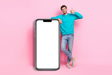 Full length photo of attractive young man lean on vertical blank banner dressed stylish blue outfit isolated on pink color background