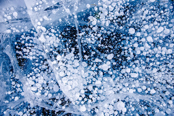Gas methane bubbles frozen in winter ice of lake Baikal, abstract background