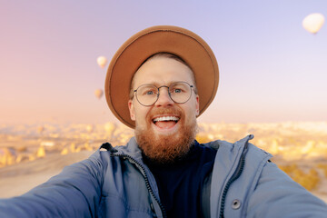 Happy man tourist making selfie photo background hot air balloons in Cappadocia Turkey