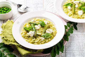 Risotto with green pea and asparagus with robiola cheese. Homemade spring rice food on a white table.