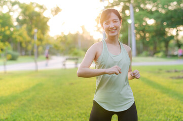 Female jogger. Fit young Asian woman with green sportswear stretching muscle in park before running...
