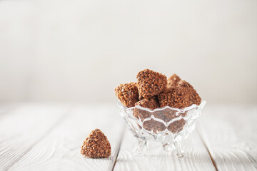 Falling chocolate truffles covered wafer crumbs. Praline chocolates in a bowl
