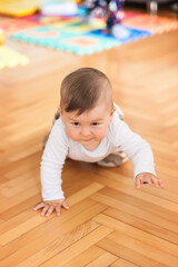 Cute baby boy crawls on the home floor, explore the world and learn to move. Front view. Love and family emotion