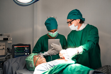 Expert medical team and their assistants collaborate in the operating room at the hospital,...