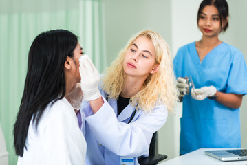 Caucasian woman dermatologist doctor examining asian young adult patient in clinic. Skin care and beauty clinic business industry