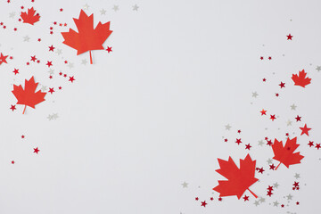 Party concept for celebrating Canada's Day. Top view flat lay of red maple leaves, stars confetti on white background with empty space for greeting or promo