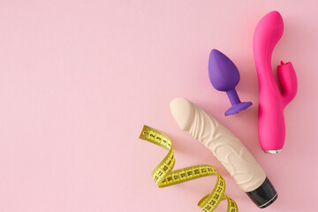 The importance of sex toy size theme. Top view flat lay of measuring ribbon, vibrator, dildo, anal...