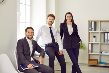Team of three young business people or corporate employees in office. Group portrait of two happy...