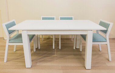 A white table and four pulled chairs stand in the room, office furniture design