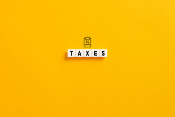 White letter blocks on yellow background with the word taxes. Tax percent or ratio