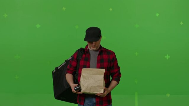 Caucasian male courier passing a box of pizza on green screen chroma key background. Man hold wireless bank payment POS terminal to process acquire credit card payment. Copy space mock up advertising