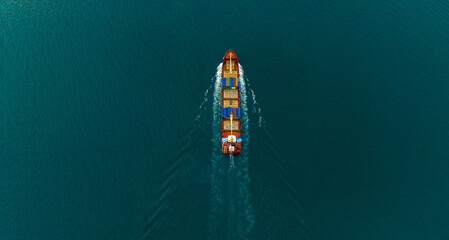 Aerial Stern of cargo container ship with contrail in the ocean ship carrying container and running for export concept technology freight shipping by ship at sunset