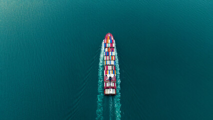 Aerial Stern of cargo container ship with contrail in the ocean ship carrying container and running for export concept technology freight shipping by ship at sunset