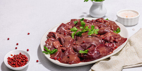 Raw chicken liver on stone background. Fresh ingredients ready for cooking, parsley, red pepper