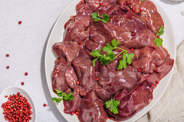 Raw chicken liver on stone background. Fresh ingredients ready for cooking, parsley, red pepper