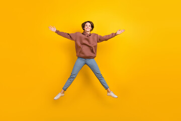 Fototapeta na wymiar Full size photo of overjoyed satisfied girl jumping raise hands make star figure isolated on yellow color background
