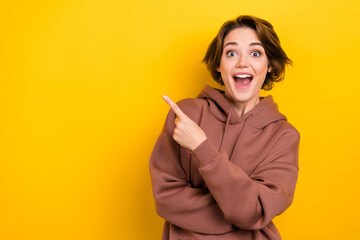 Photo of amazed funny girl indicate finger empty space sale offer price wear brown hood shirt...