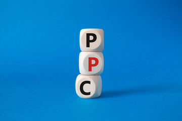 PPC - Pay Per Click symbol. Wooden cubes with words PPC. Beautiful blue background. Business and PPC concept. Copy space.