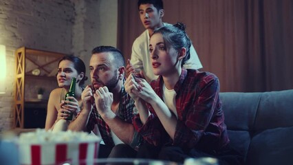 Young friends, men and women sitting on couch at home and watching football match on tv. Sport fans cheering up favourite team. Winning game. Concept of leisure time, sport fans, friendship, emotions
