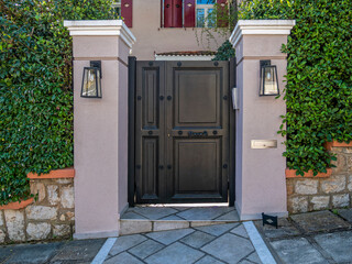 A luxury house entrance dark charcoal painted iron door by the sidewalk. Travel to Athens, Greece.