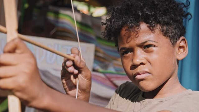 Slowmo stable medium closeup of African American elementary age boy taking aim and doing toy archery