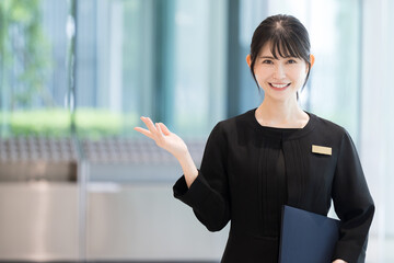ホテルの受付や案内する接客業の笑顔の日本人女性イメージ　正面のカメラ目線　コピースペースあり - obrazy, fototapety, plakaty