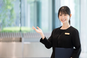 ホテルの受付や案内する接客業の笑顔の日本人女性イメージ　正面　使いやすいコピースペースあり