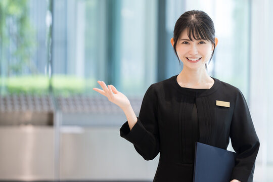 ホテルの受付や案内する接客業の笑顔の日本人女性イメージ　正面のカメラ目線　コピースペースあり