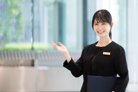 ホテルの受付や案内する接客業の笑顔の日本人女性イメージ　正面　使いやすいコピースペースあり