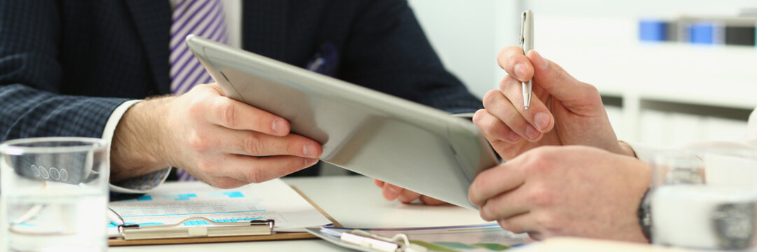 Businessman analyzes graph using touchpad of digital tablet. Business people reporting on financial charts and summarizing financial growth