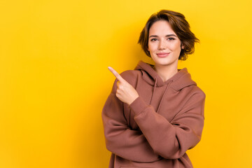 Photo of lovely positive person indicate finger empty space news isolated on yellow color background