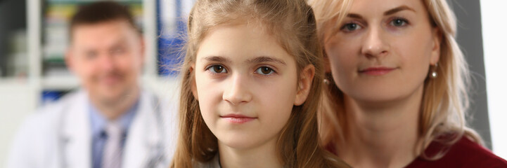 Portrait of mother and daughter on background of pediatrician medical doctor. Medical examination and family insurance concept