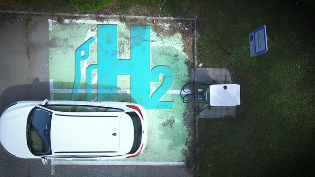 Aerial view above a Hydrogen car parking at a refill station, tanking with h2