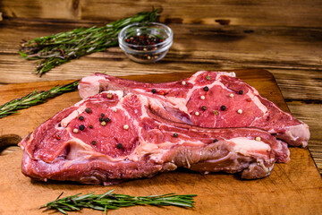 Raw ribeye steak, glass jar with spices and rosemary on cutting board