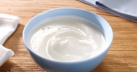 Sour cream in a bowl on a wooden background. Close up. High angle view.