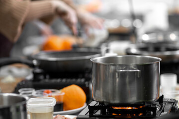 Chef cooks in kitchen restaurant, closeup details of preparation of dishes in frying pan and saucepan
