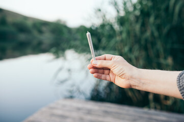 Сannabis joint man holding in his hand in nature smoking marijuana