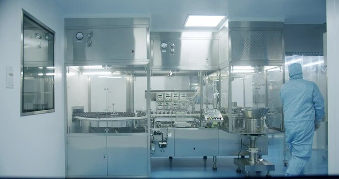 Sterile Pharmaceutical Manufacturing Laboratory where Scientists in Protective Coveralls. Factory Cleanroom. Pharmaceutical, Biotechnological and Semiconductor Creating Manufacturing Process.