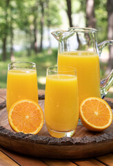 Orange juice in glasses and pitcher with sliced oranges