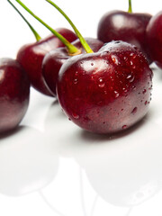 Several ripe red cherries on a white background close-up. Selective focus. Vertical. Studio shot.